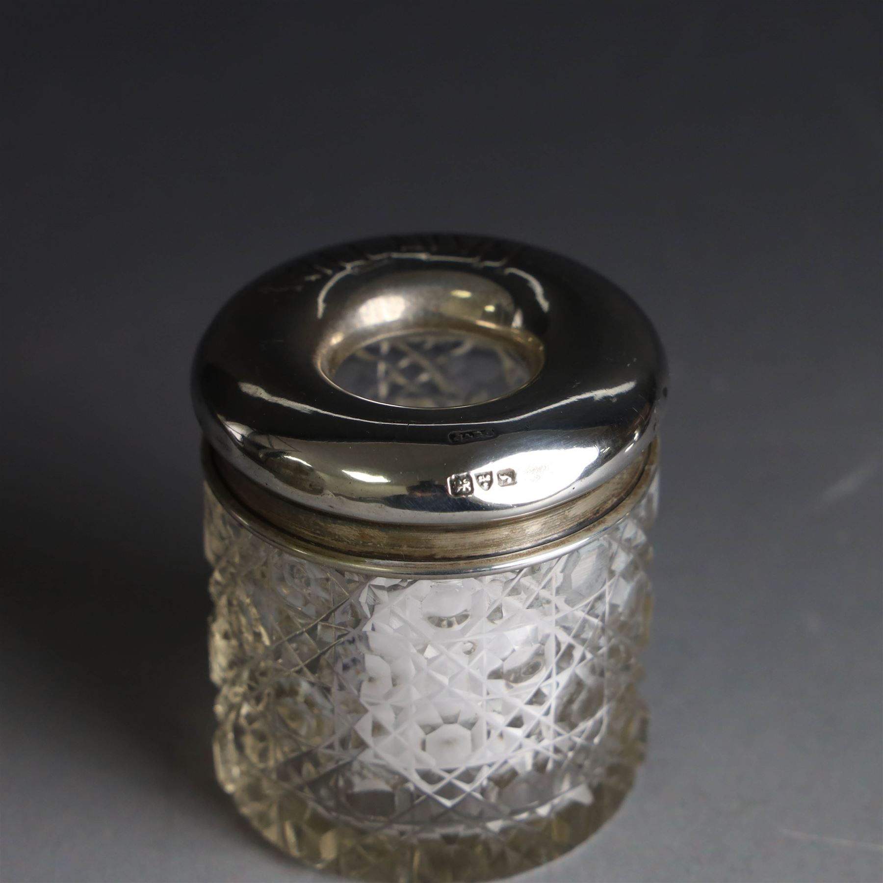 Edwardian silver fall-front ring box with loop handle, opening to reveal velvet interior with five ring spaces, hallmarked Deakin & Francis, Birmingham 1907, together with a cut glass jar with silver lid inscribed 'Hair Tidy' and a silver mounted capstan inkwell, both hallmarked 
