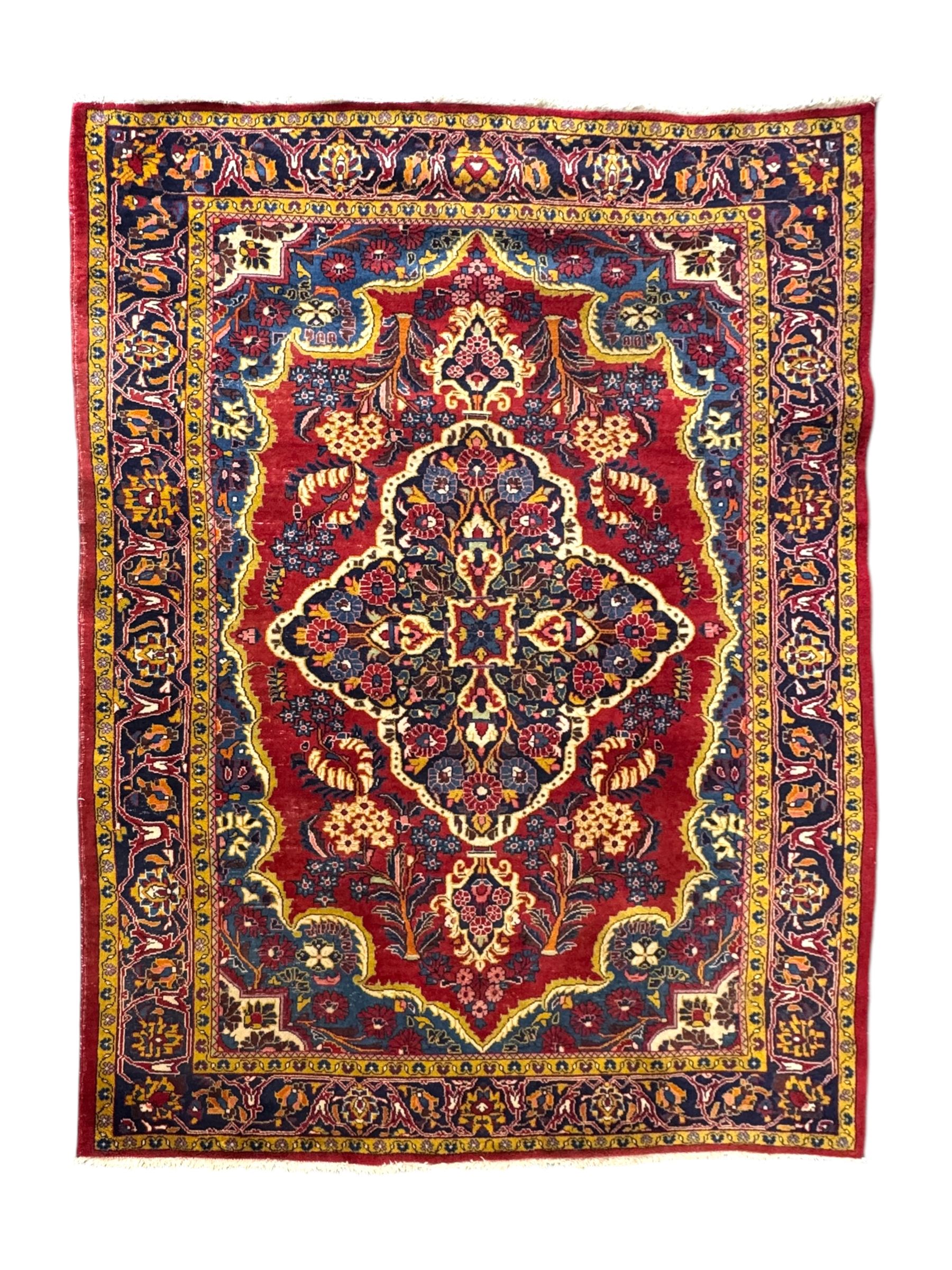 Mid-20th century Persian ground rug, featuring a bold red field and large lobed medallion, flanked by floral corner spandrels, enclosed within multiple borders of stylised vines and palmettes, with fringe to both ends