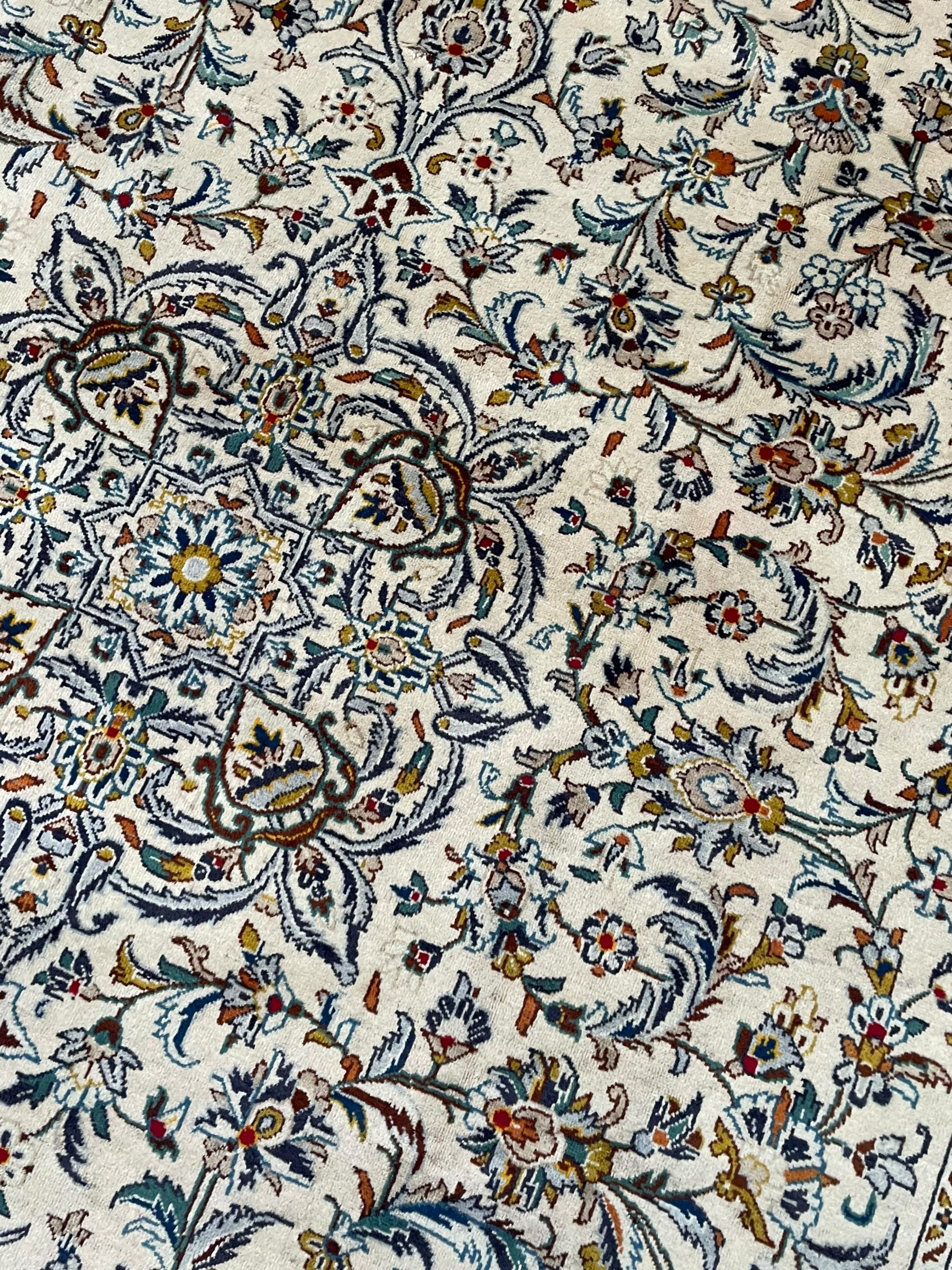 Persian Kashan ivory ground carpet, central pole medallion surrounded by swirling leafy branches and stylised plant motifs, scrolled foliate spandrels, the main border decorated with scrolling pattern and repeating palmettes, within floral patter guard stripes 