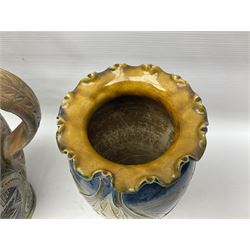 Early 20th century Royal Doulton stoneware vase, decorated with a stylized floral design below a wavy rim, monogrammed B.N, possibly for Bessie Newbery, H28cm, together with an early 20th century glazed jug, heavily carved throughout (2)