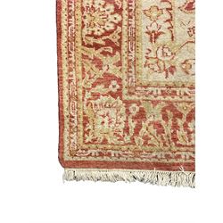 Persian design beige and crimson ground rug, the field decorated with interlacing scrolled foliage, repeating border within guard stripes 