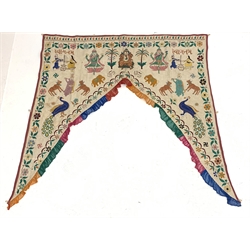 Early 20th century Indian Toran, embroidered in bright colours with figures and animals and Ganesh seated to the centre, within a floral trailing border and ruffle trim, W112cm x 115cm 