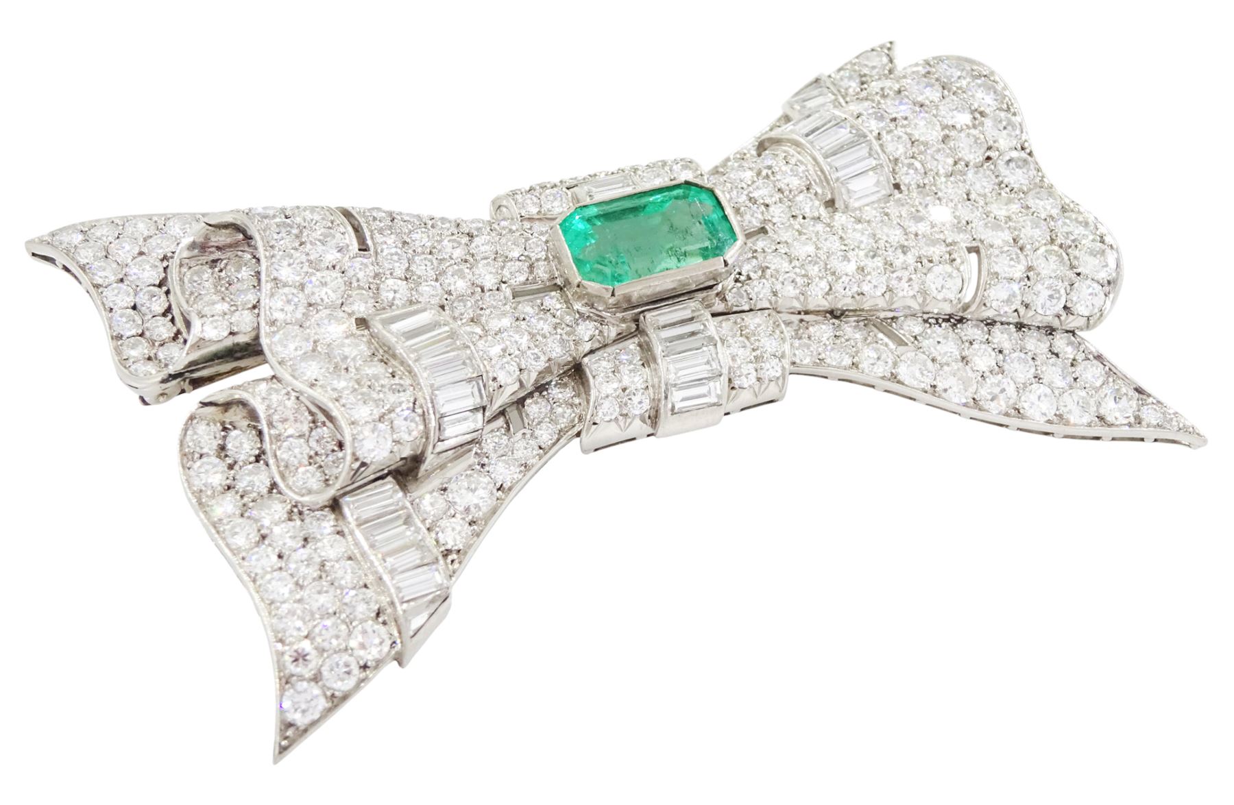 Platinum emerald and diamond bow brooch, central octagonal cut emerald of approx 4.00 carat, with round brilliant and baguette cut diamond surround, total diamond weight approx 23.00 carat