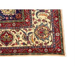 Northwest Persian signed Tabriz ivory ground carpet, central medallion with intricate floral motifs, the field and spandrels decorated with scrolling tendrils and palmettes, ivory main border with crimson and indigo floral decorations, surrounded by crimson guard bands