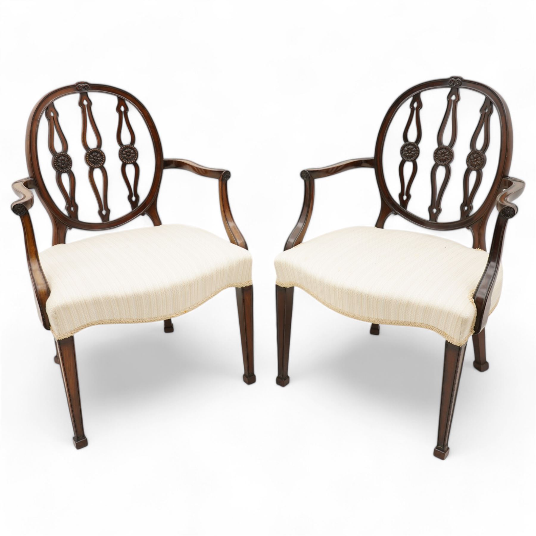 Set of six (4+2) late 19th to early 20th century Hepplewhite design mahogany dining chairs, moulded oval framed back with three shaped and pierced upright rails decorated with floral carved roundels, upholstered in pale fabric, on square tapering supports with recessed panels and block feet 