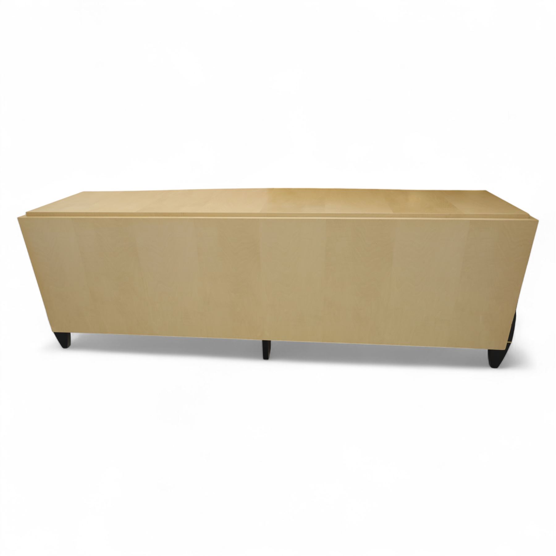Contemporary maple veneered sideboard, serpentine glass top over six graduating Blum soft-close drawers, raised on curved black and gilt accented supports