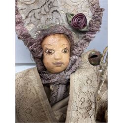 Modern reproduction automaton in the form of a baby doll in a basket clothed in Victorian style lace bloomers and frilled bonnet; clockwork action; on raised platform; with French paper label on base, 29cm wide,