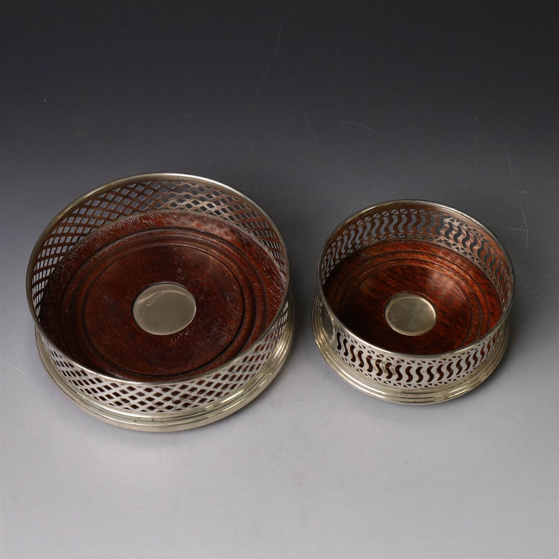 Two silver mounted bottle coasters, the larger example with latticework sides, hallmarked Mappin & Webb Ltd, Birmingham 1993, the smaller example with pierced sides, hallmarked W I Broadway & Co, Birmingham 1998, largest D12cm