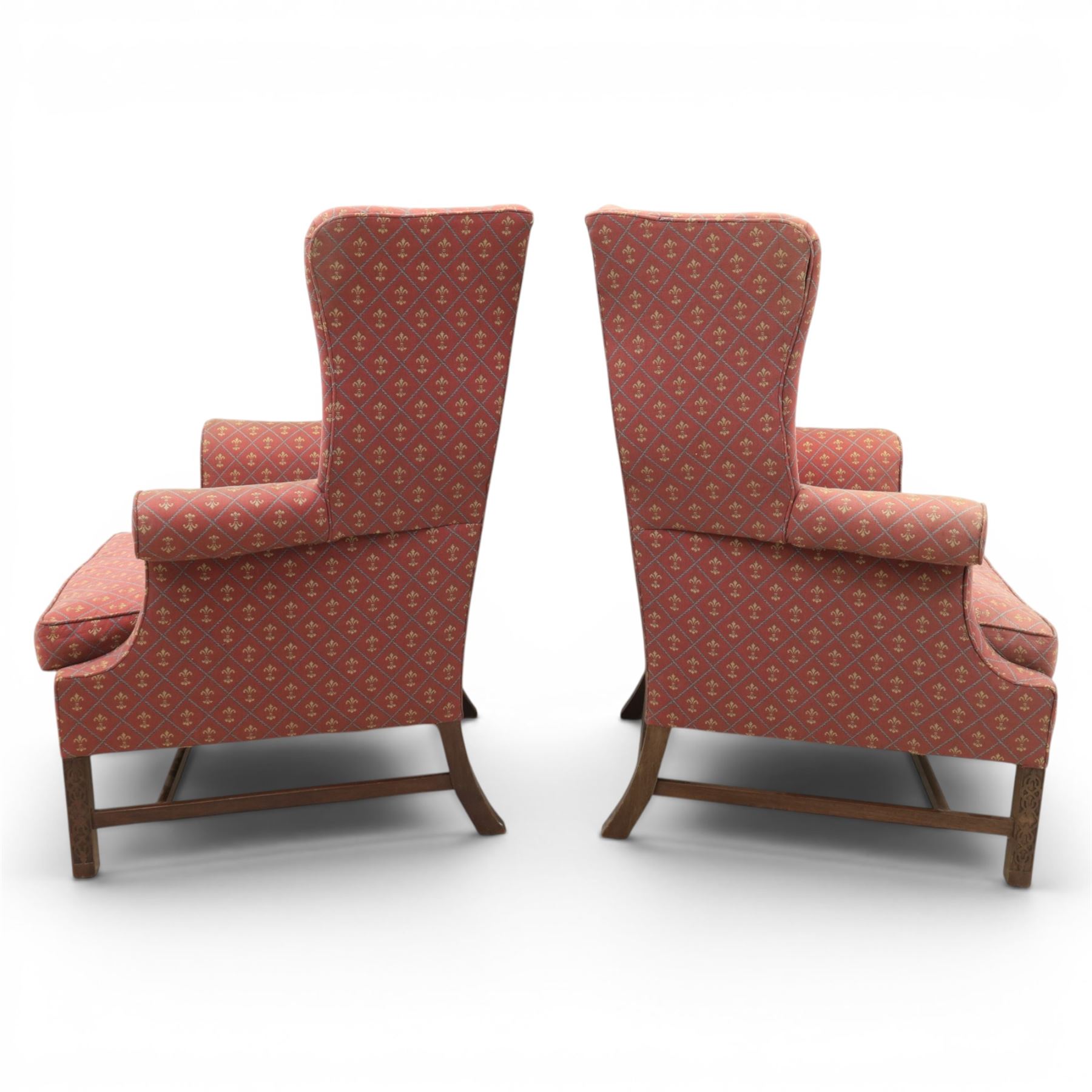 Georgian design wingback armchairs, the high backs flanked by shaped wings over padded scroll arms, upholstered in burgundy and gilt fleur-de-lys patterned fabric, loose cushion seats, raised on square tapering front supports