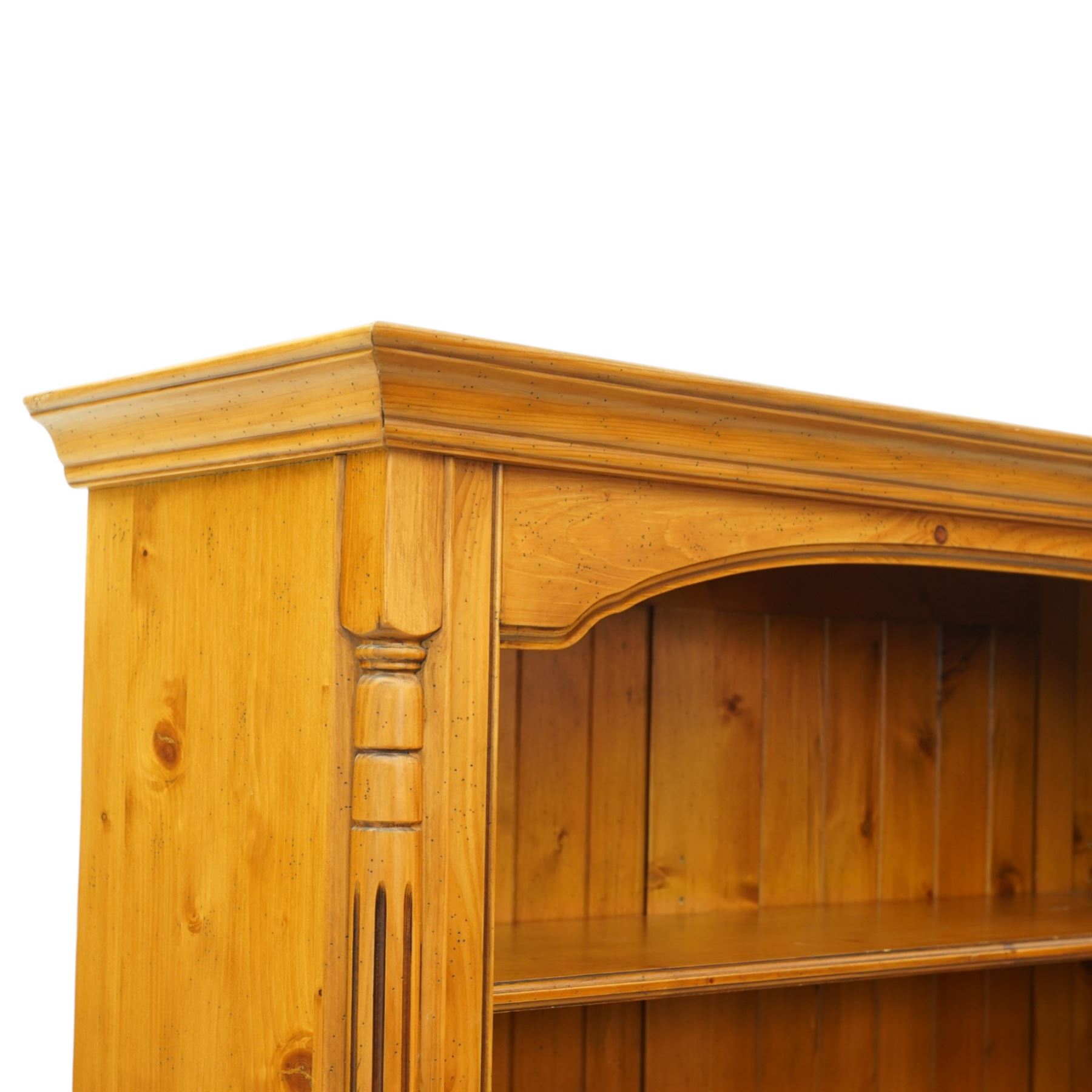 Late 20th century traditional waxed pine open bookcase, moulded cornice above a shaped frieze, open front with fixed shelves and boarded back, flanked by fluted pilasters