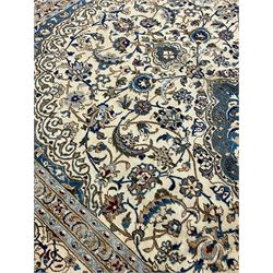 Persian Nain ivory ground carpet, the field decorated all over with leafy branches and stylised flower head motifs, blue ground central medallion and matching spandrels decorated with trailing foliate pattern, repeating guarded border with overall floral design
