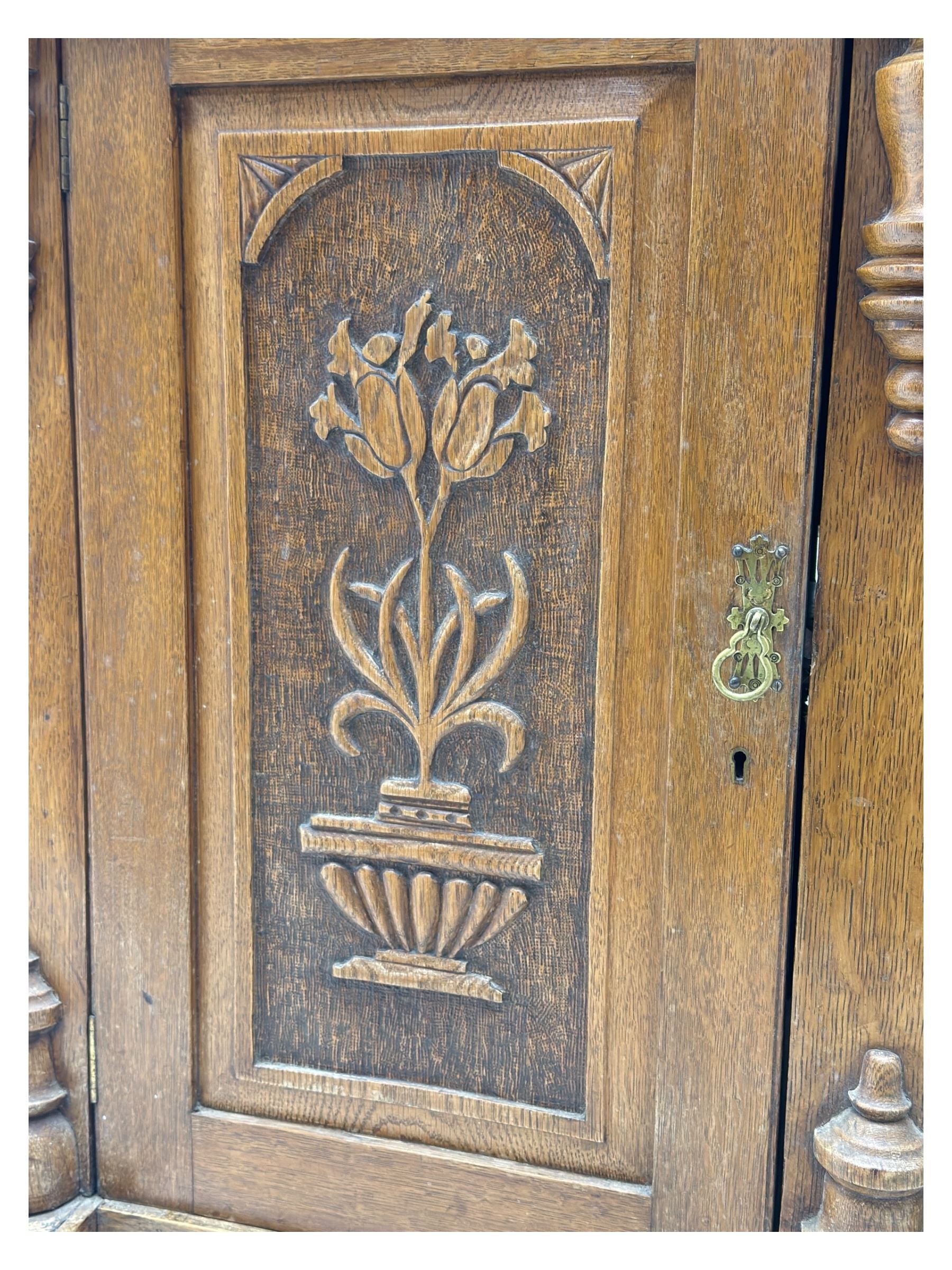 Late 19th century pine dresser, the projecting cornice with dentil and spindle moulded frieze above a three-tier plate shelves, flanked by glazed doors, the base fitted with three frieze drawers over arched apron and carved floral panelled cupboard doors, raised on turned feet