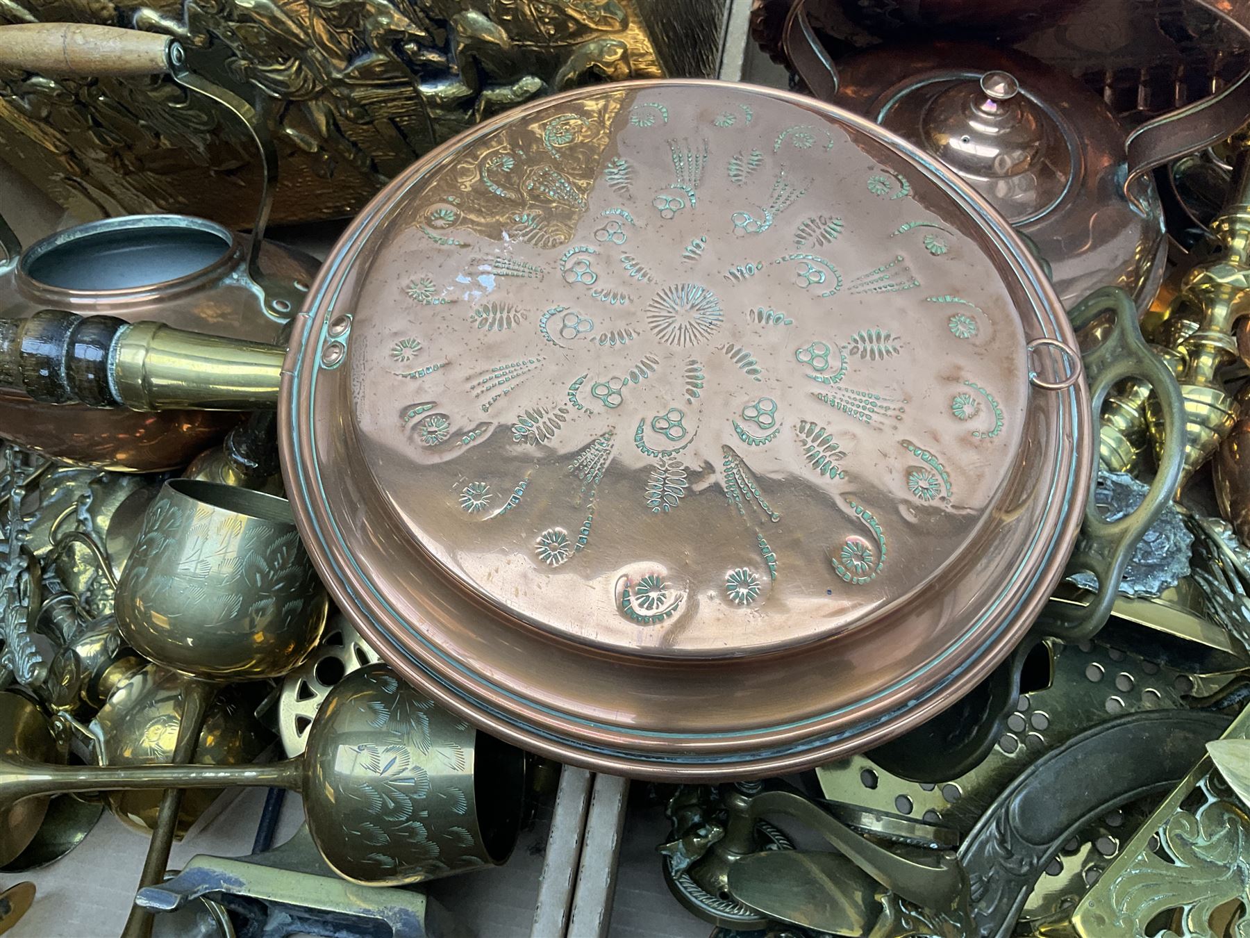 Quantity of copper pans and teapots, dish and sieve with pierced heart decoration and brass handle, together with quantity of brassware to include brass Art Nouveau crumb tray and brush, repousse chargers, fire tool accessories, decorative canon, sword and guns etc