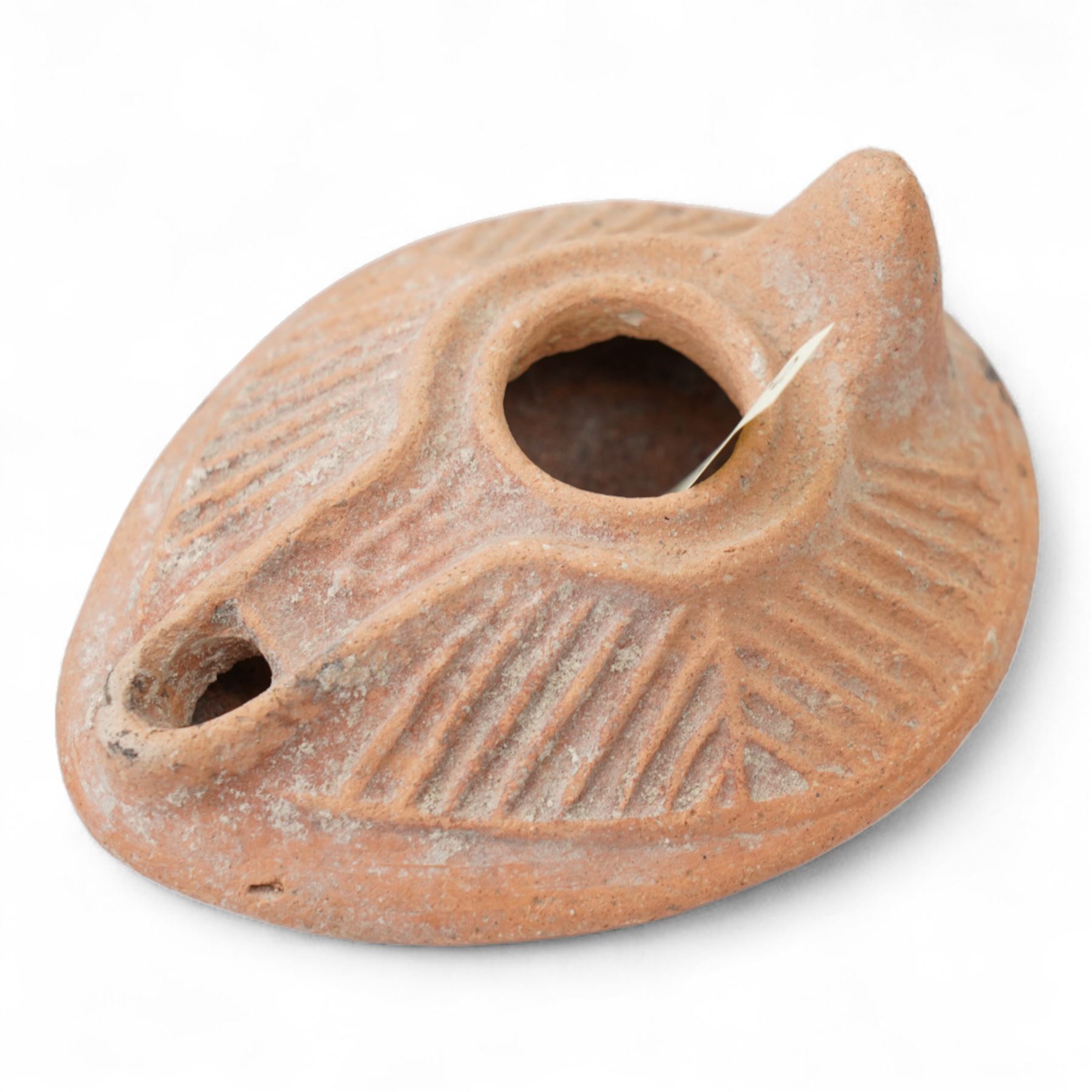 A group of four Byzantine terracotta oil lamps - Eastern Mediterranean, c.5th-7th century AD, comprising a group of mould-made slipper-form oil lamps, each with a rounded body, large central filling hole, and a short to elongated nozzle; including one with fine radiating linear decoration, and another preserving ancient use with traces of oil and wick residue within the burnished interior; together with a Crusader-period terracotta oil lamp (c.12th-13th century AD) of angular form with recessed panel decoration and a pierced handle moulded as a stylised animal head
Provenance: By the vendor’s repute, acquired/collected in the Middle East (Dead Sea area/Syria) in the 1960s