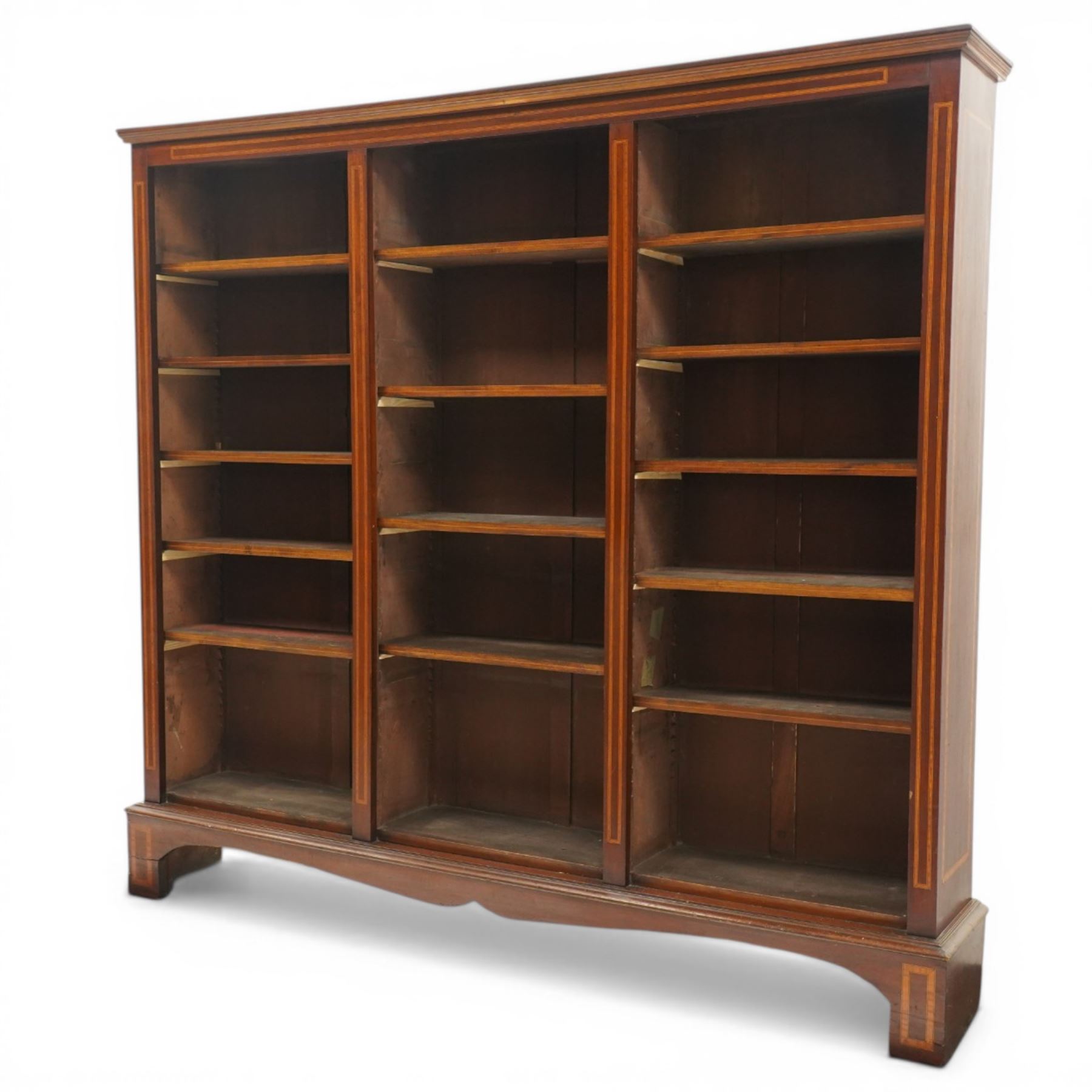 Quality Edwardian inlaid mahogany triple-column open bookcase, projecting cornice over a satinwood banded frieze, fitted with fourteen adjustable shelves with strung facias, the shaped apron on bracket feet