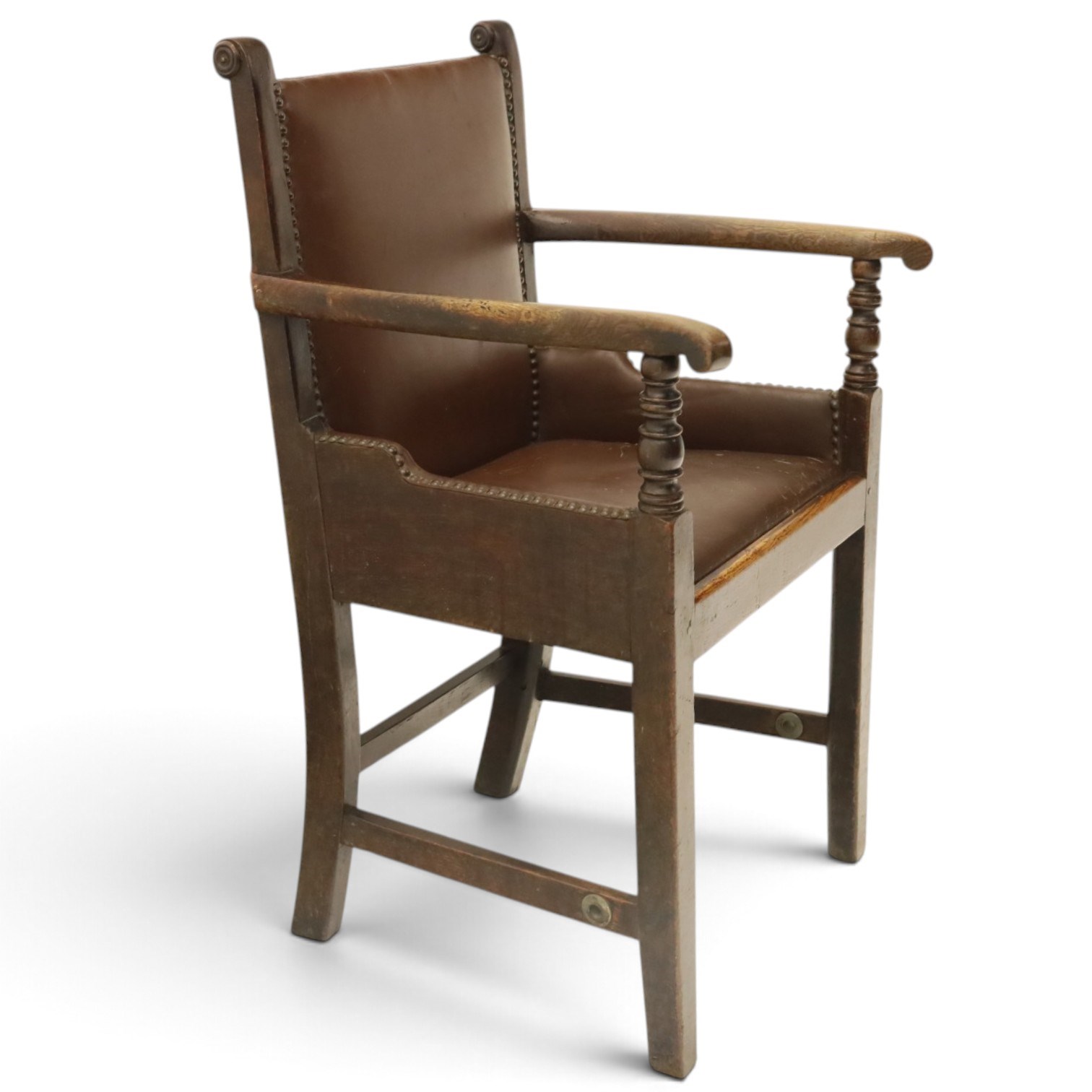 DD CL - Early 20th century oak open armchair, rectangular back with scrolled uprights, brown upholstered back and seat with brass stud edging, shaped open arms on turned supports, square legs united by stretchers