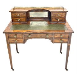 Late Victorian inlaid rosewood writing desk, the raised back fitted with ornate gilt metal gallery, bevelled mirror and four small drawers, rectangular top with leather inset over one long and four short drawers, square tapering supports with brass and ceramic castors