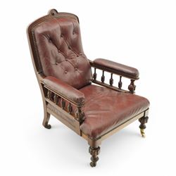 Late Victorian mahogany open armchair, arched cresting rail decorated with turned roundel, upholstered in buttoned burgundy leather, the upholstered arms on turned and lobe carved balustrade, turned and lobe carved front feet with brass and ceramic castors 