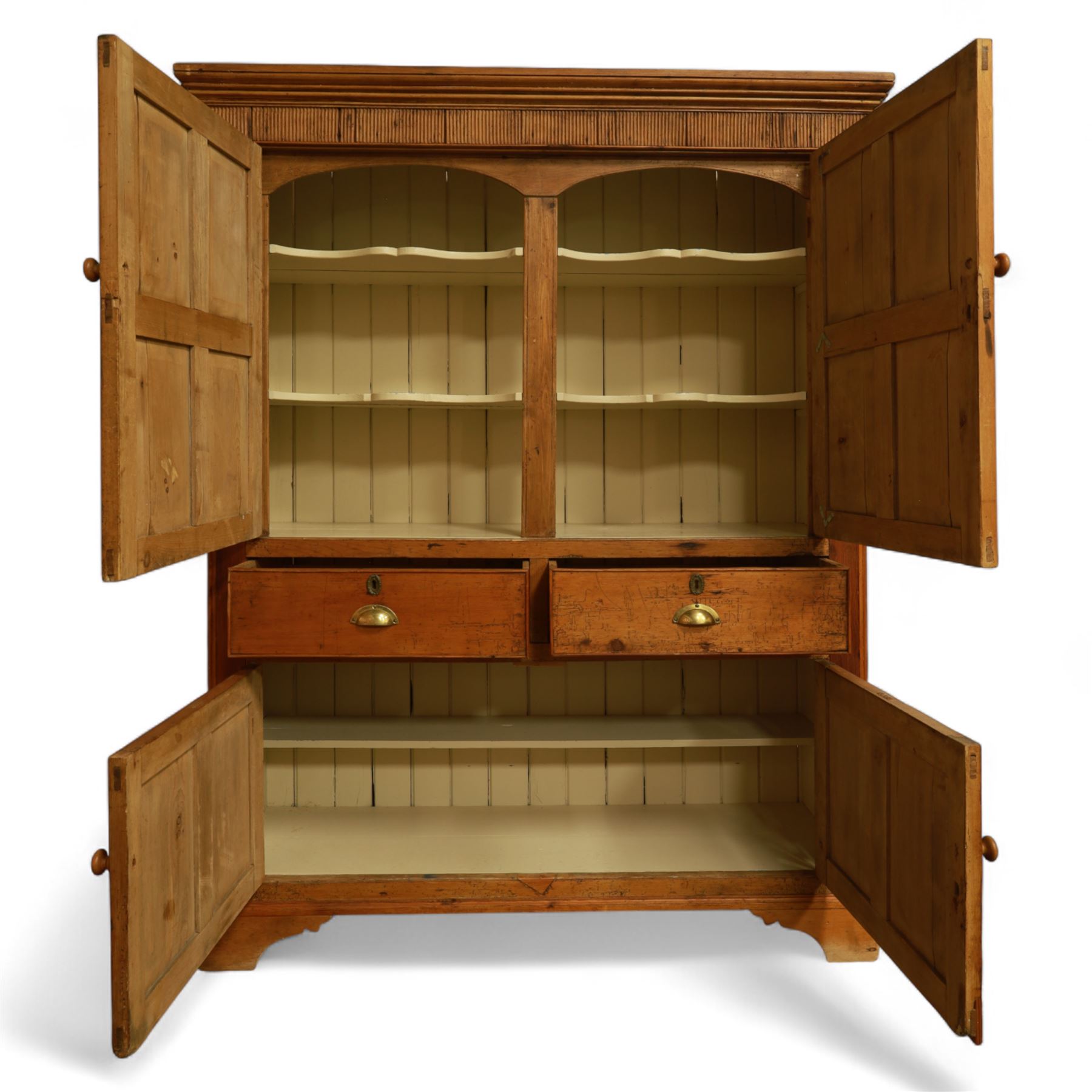 Victorian stripped pine kitchen cupboard, of rectangular form with fluted cornice and top section with two panelled cupboard doors revealing painted shelved interior, middle with two drawers with turned knob handles and brass cup handles, base section with two panelled cupboards, raised on shaped bracket feet 