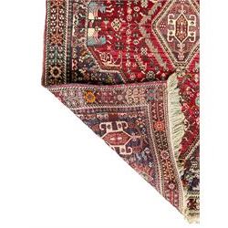 Persian Heriz crimson ground rug, field with large central lozenge surrounded by stylised plant motifs in a mauve background, guarded border with repeating foliage