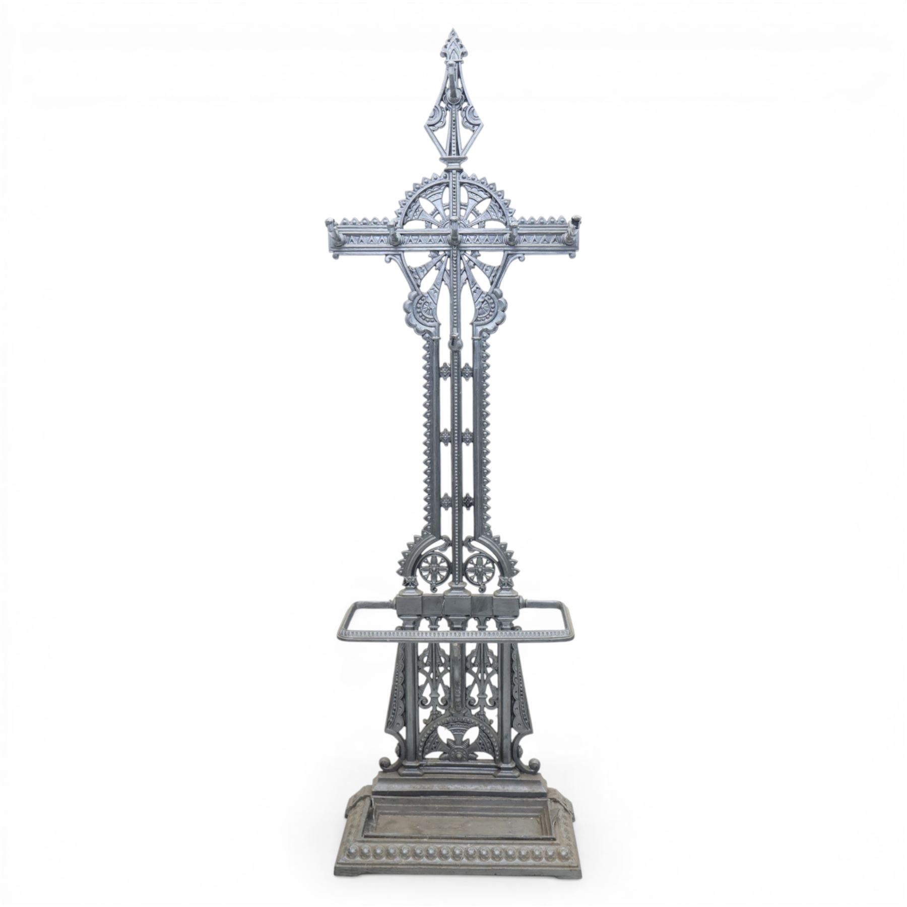 Late 19th century cast iron hall stand in the style of Christopher Dresser, cross shaped upper section with radiating wheel motif and applied hooks, architectural upright with pierced Gothic and geometric detail, fitted with rectangular drip tray and pierced surround, raised on stepped plinth base with bead decoration