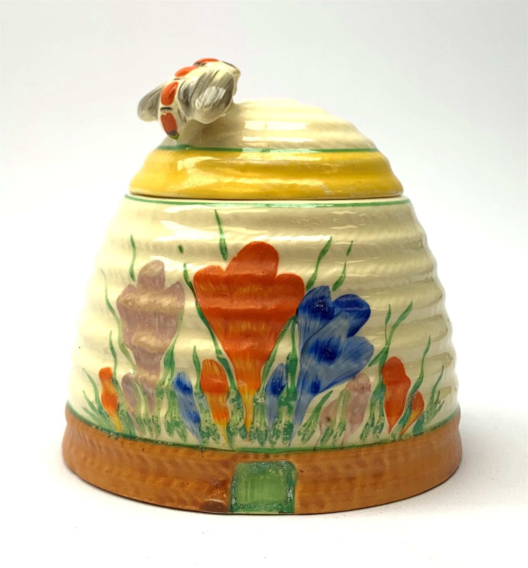 A Clarice Cliff Newport Pottery honey pot, modelled in the form of a beehive and decorated in the Crocus pattern, H10cm.