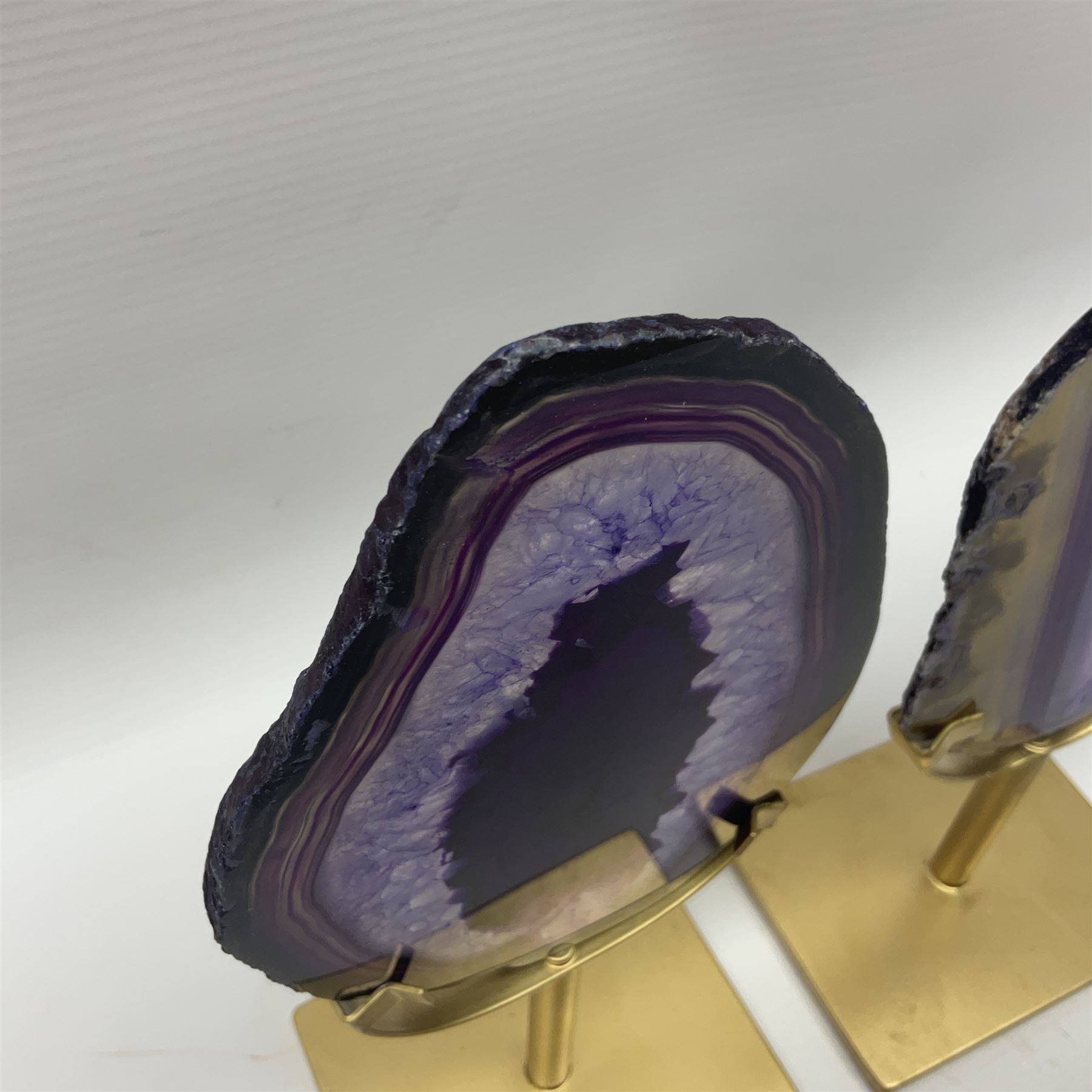 Pair of purple agate slices, polished with rough edges raised upon gilt metal stands