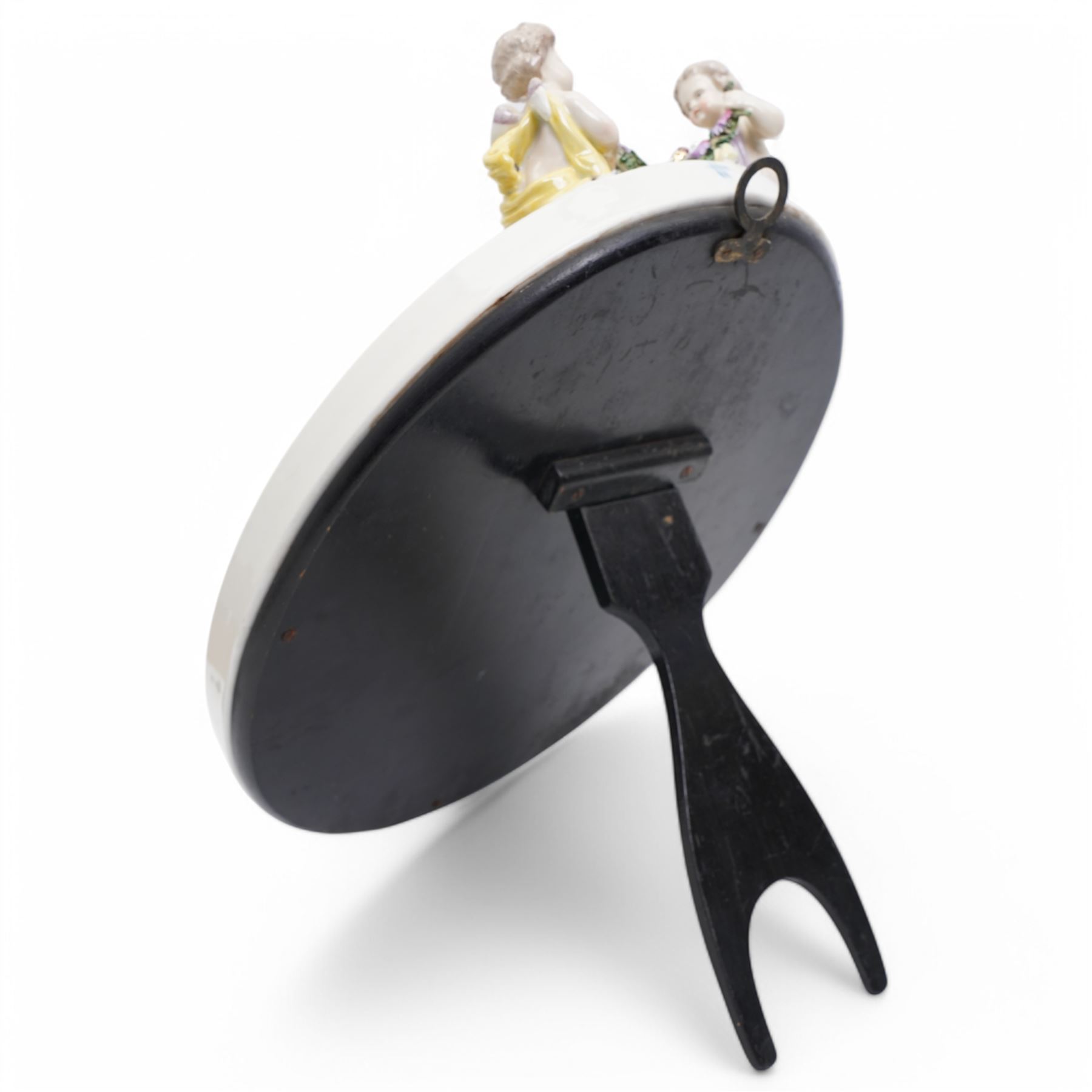 Sitzendorf oval table mirror with two cherubs holding a floral garland above foliage and insects etc on easel stand 40cm x 31cm