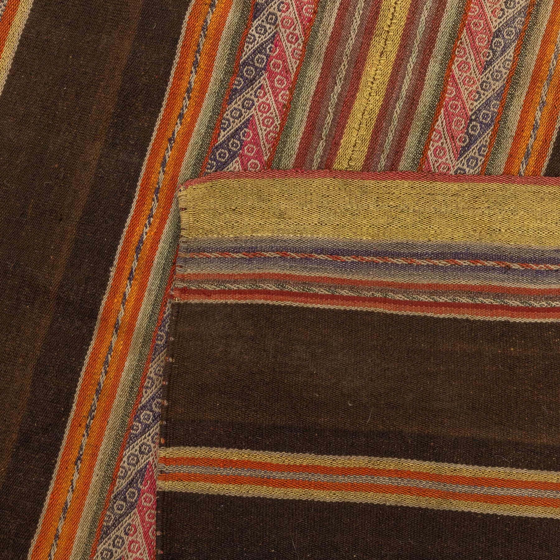 Flatwoven wool rug, with horizontal bands in dark brown, rust, ochre and muted red tones, detailed with narrow geometric patterned stripes across the field