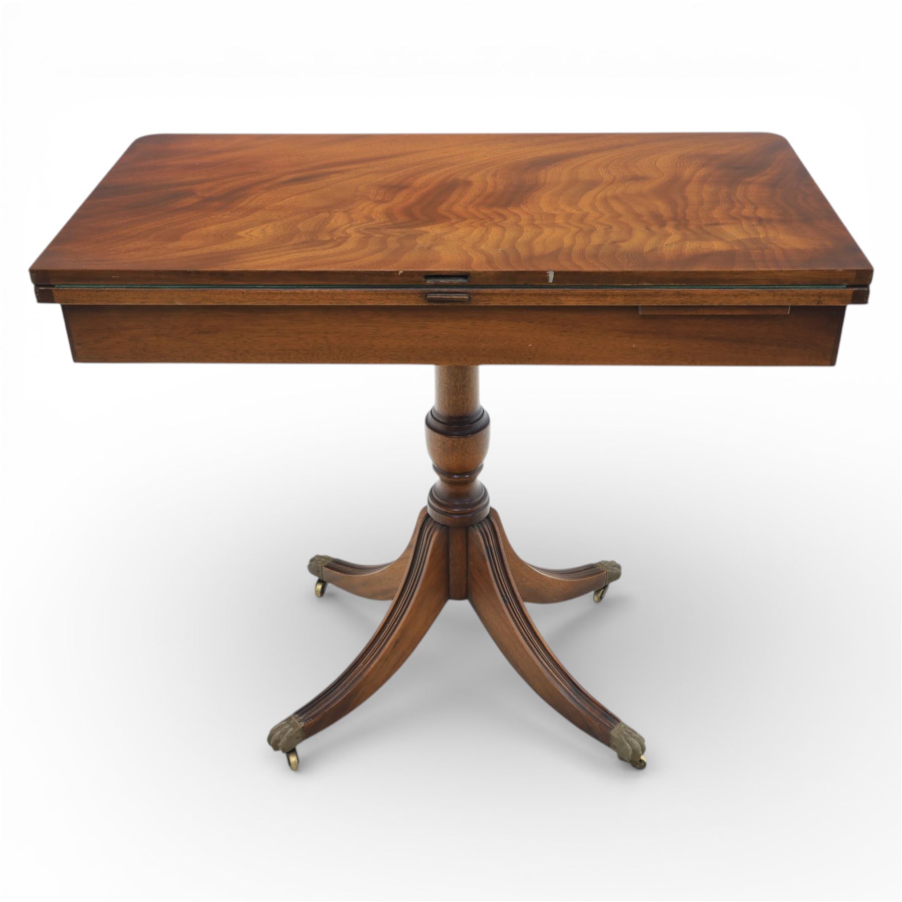 Victorian design mahogany card table, rectangular top with swivel and fold open action, revealing a baized lined interior, raised on turned baluster column, with reeded legs terminating in brass paw castors 