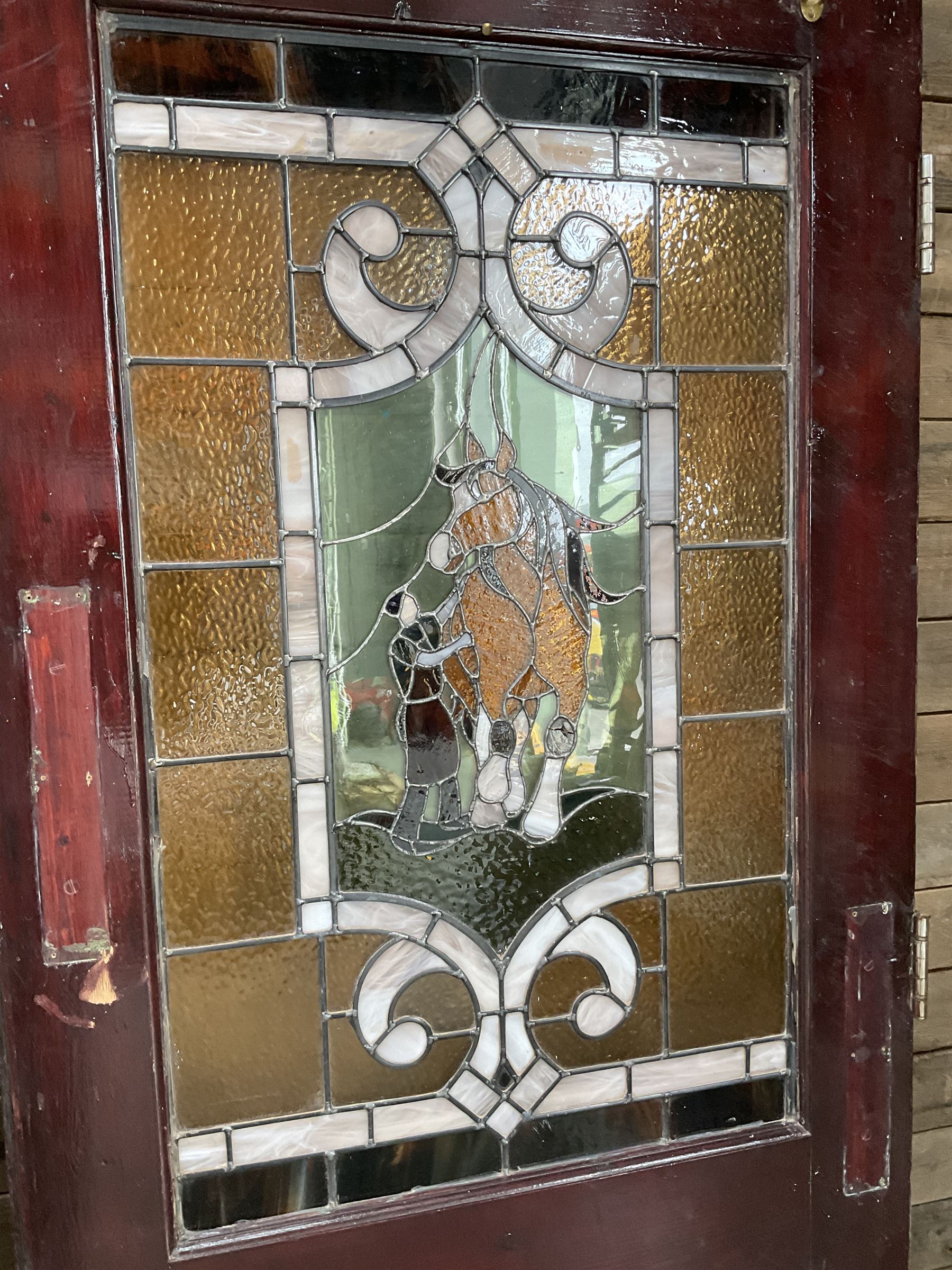 Two early to mid 20th century timber doors, set with lead framed stained glass panels depicting agricultural worker and horse