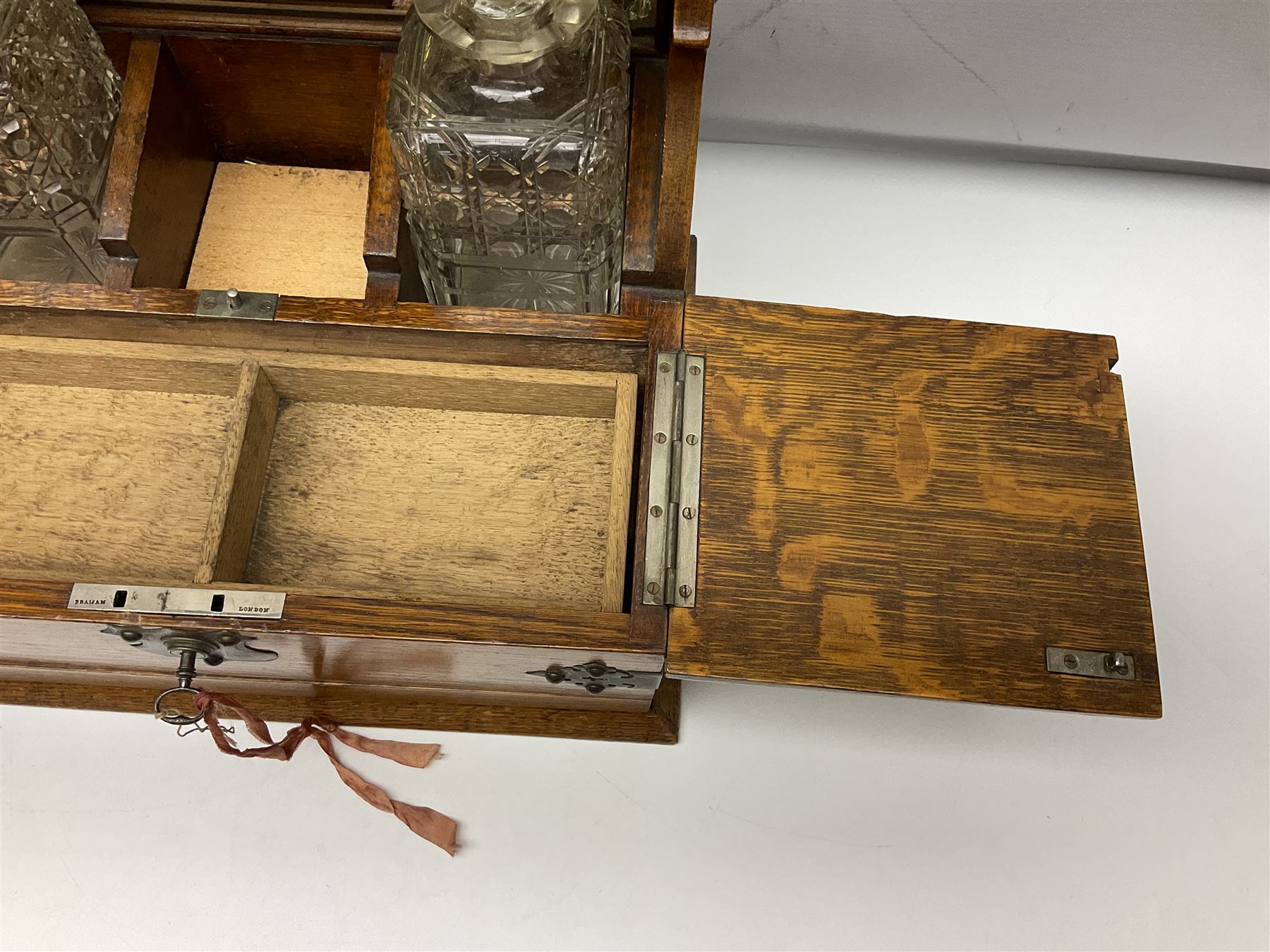 Victorian oak tantalus, mirrored high-back with recess for housing the decanters, behind a hinged box, with cribbage board to the concealed drawer below, marked Barman, London, H33cm, L37cm