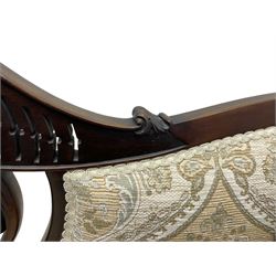 Late Victorian mahogany framed two-seat salon settee, shaped cresting rail pierced and carved with foliate decoration and C-scrolls, upholstered in pale fabric with foliate pattern decorated with stylised plant motifs, shaped and scroll carved arms terminating to shell carved cabriole feet, on brass and ceramic castors