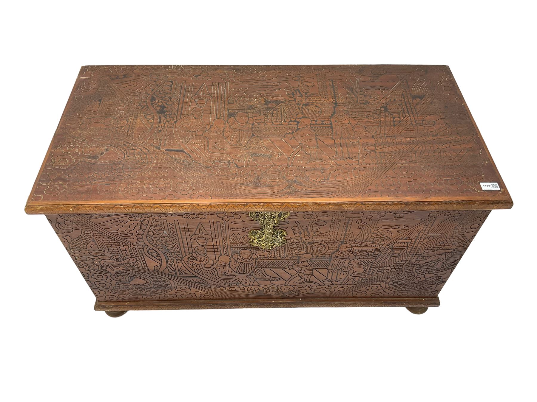 Hong Kong camphor wood chest, rectangular hinged top, carved all over with traditional scenes and dragon boats, on bun feet