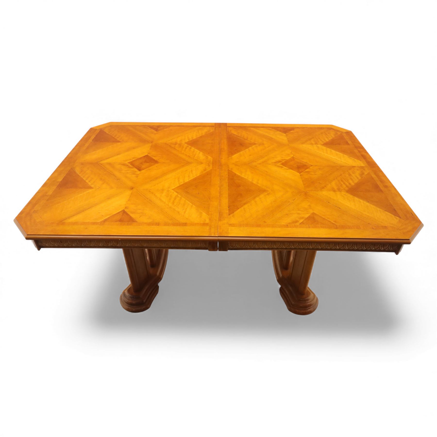 Late 20th century parquetry veneered extending dining table and eight chairs, the rectangular top with canted corners decorated with geometric parquetry panels, moulded edge frieze with repeating carved detail, raised on twin pedestal supports with fluted columns and shaped platform bases, the chairs with pierced splat backs and upholstered drop-in seats
Extends on a central leaf to 208cm