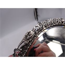 Continental silver miniature dressing table/wall mirror, of oval form with bevelled mirror plate, surrounded by a bead and dart rim, with pierced scrolling floral border with a standing cavalier to either side and the bust of a cavalier to the base, H17.7cm
