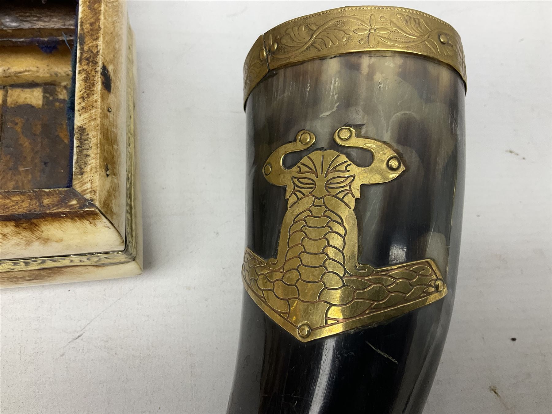 Swiss mountain hunters tobacco pipe with a horn mouthpiece, metal hinged pierced lid and brass chain, the black coated body adorned with small metal cow flowers, together with two other pipes and case, brass mounted horn, brass mounted bone box, carved mother of pearl handled knife and fork and brass jug