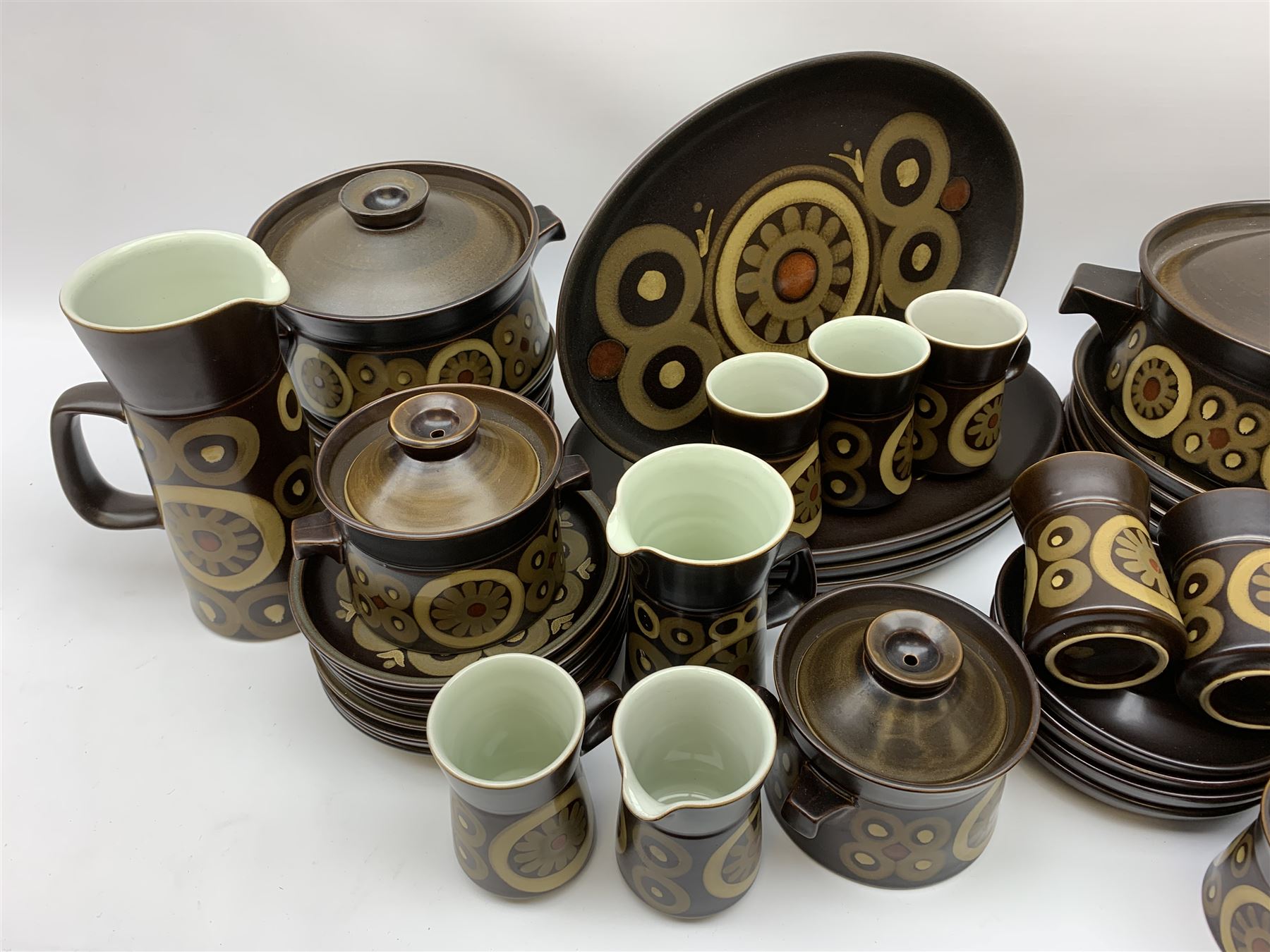 Denby Arabesque patter tea and dinner wares, comprising six dinner plates, twelve side plates, six twin handled bowls and covers, two tureen and covers, four oval serving platters, coffee pot, water jug, milk jug, cream jug, sucrier and cover, and eight coffee cans. 