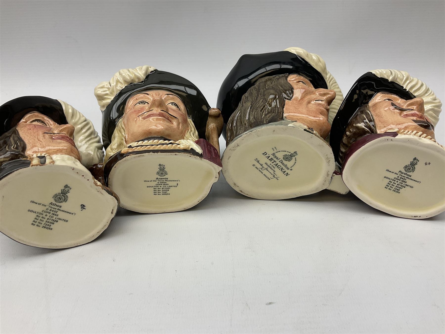 Royal Doulton eight musketeers character jugs, comprising four large jug Aramis D6441, Athos D6439, Porthos D6440, and D'Artagnan D6691, and four medium sized jugs Aramis D6454, Athos D6452, Porthos D6453, and D'Artagnan D6764