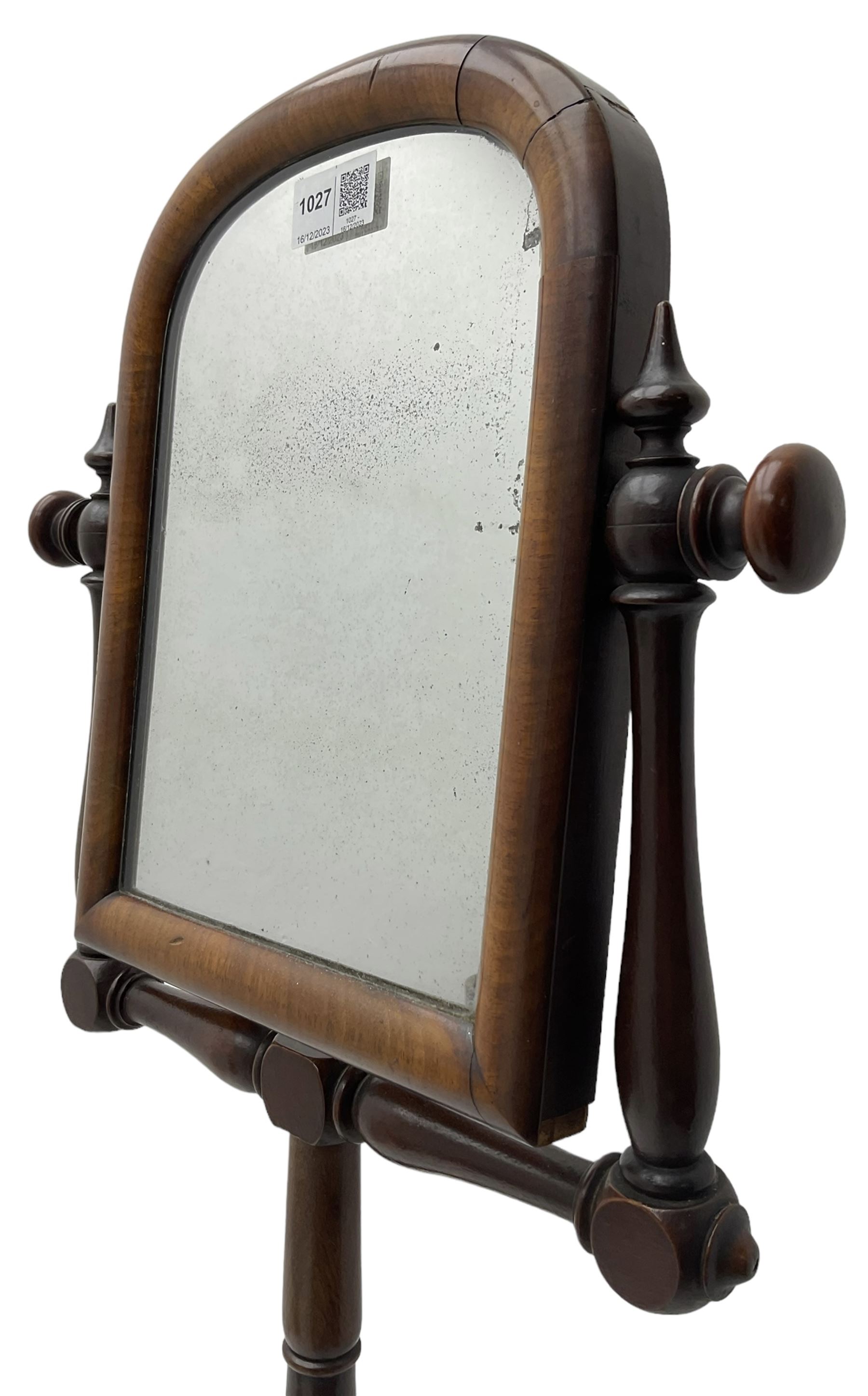 Early Victorian mahogany shaving mirror, arched frame with plain mirror plate on turned horns and supports, adjustable height mechanism on turned stem, circular platform base with four extending block feet carved with scrolled foliage 
