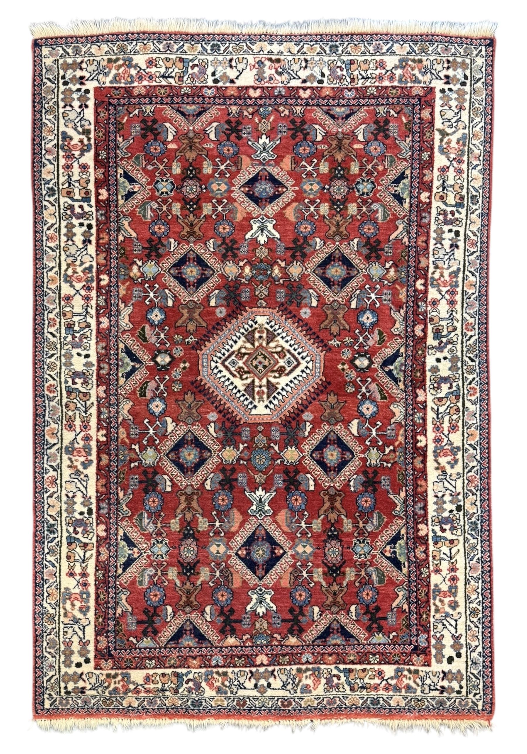 Pair of rugs one Persian hamadan rug central stepped medallion enclosing geometric motifs in ivory and brown, framed by a cream border with scrolling palmettes and fringed ends (H 156cm W 105cm), one Pakistani Bokhara rug rust red ground with repeated Tekke gul motifs within rosette and lozenged borders, fringed ends (H 98cm, W 65cm)