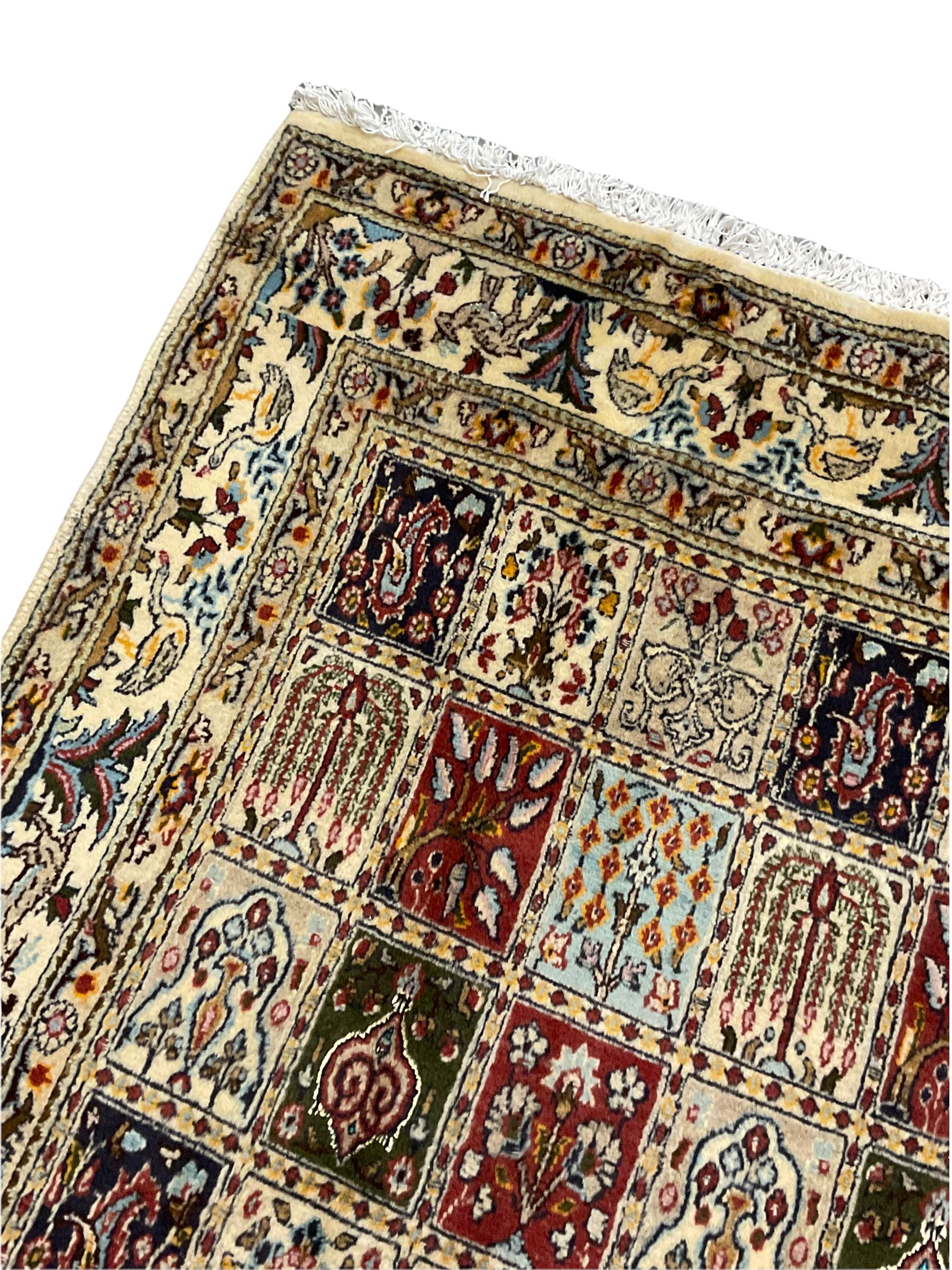 Persian Heriz design rug, ivory ground with rectangular panels each depicting garden scenes of tree of life, plants and Boteh motifs, the guarded border decorated with wildlife and bird scenes