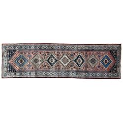 Persian Yalameh coral ground runner rug, the field decorated with seven hooked lozenge medallions surrounded by stylised plant motifs, the indigo spandrels decorated with similar patterns, guarded border with repeating diamond lozenges