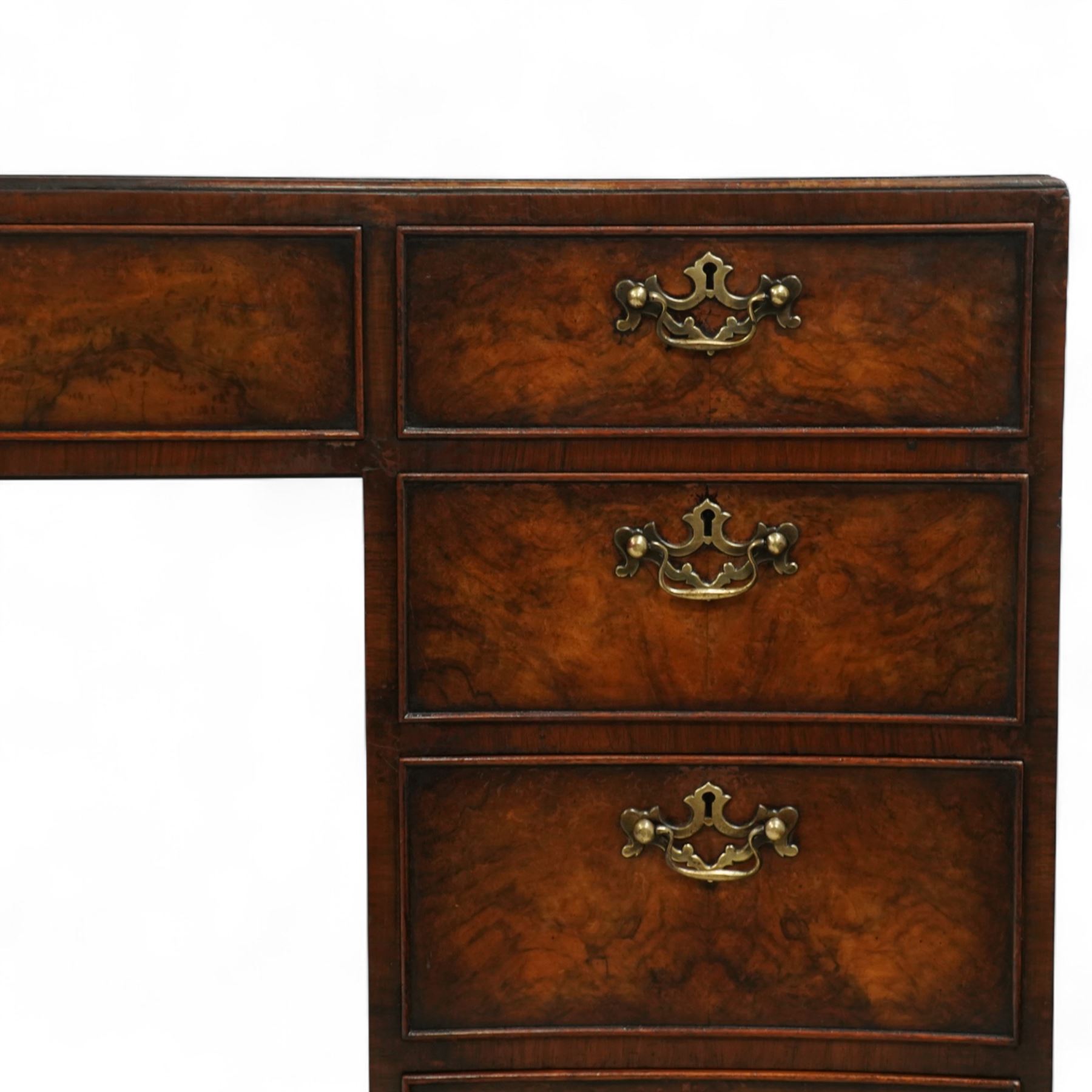 Early 20th century inlaid mahogany pedestal kneehole desk, rectangular top with inset tooled leather writing surface, over an arrangement of nine drawers with brass swan neck handles, on ogee bracket feet