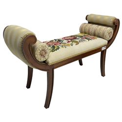 Regency design mahogany framed window seat, the scrolled arms upholstered in striped fabric, the stuffed seat in floral embroidered fabric, on sabre supports, with two bolster cushions
