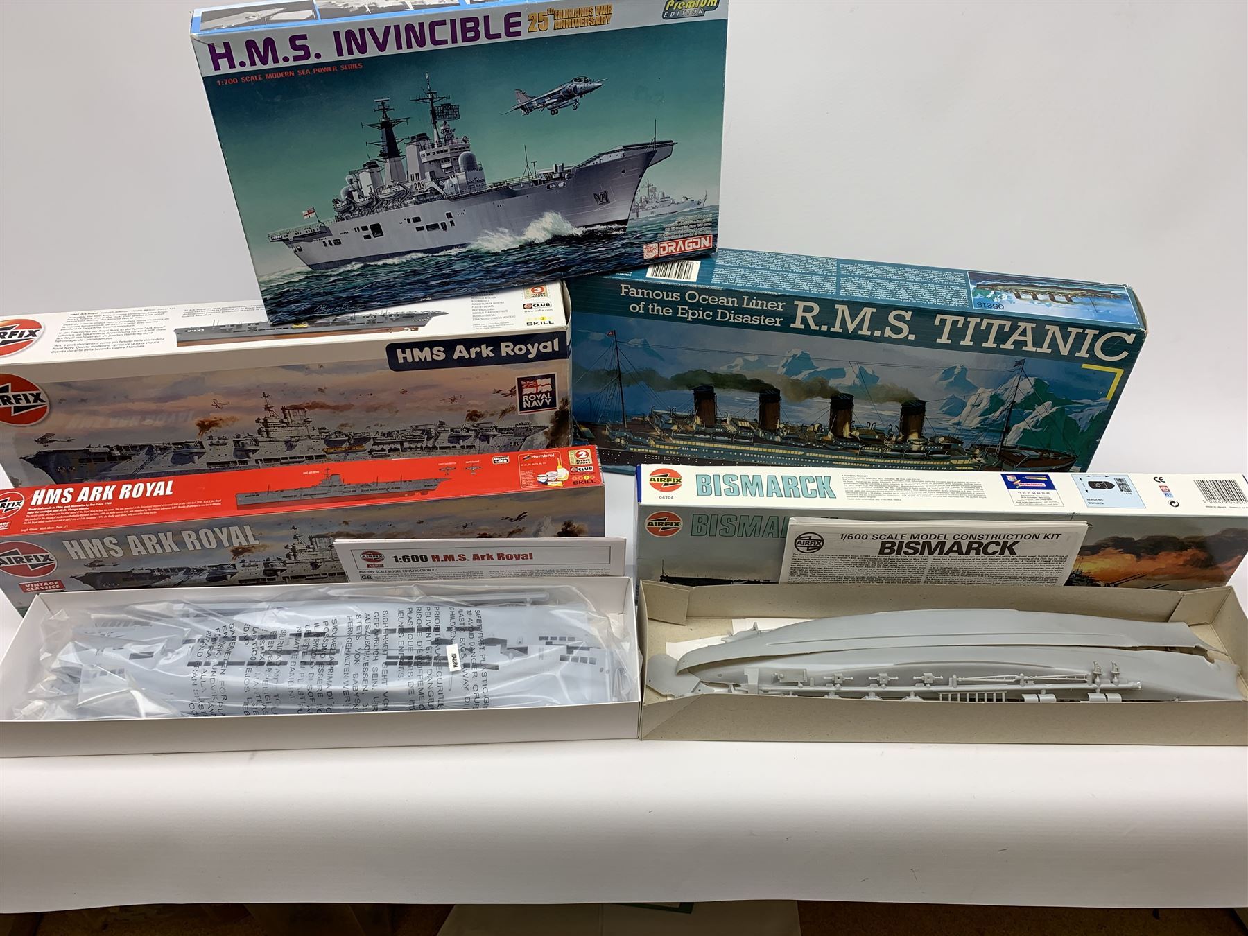 Ten plastic model kits of ships by Airfix, Revell, Dragon and Skywave, predominantly 1/600th scale including R.M.S. Titanic, HMS Invincible, two x HMS Ark Royal, HMS Fearless, HMS Hood, HMS Belfast, Bismarck etc; all boxed, most in factory sealed transparent packaging (10)