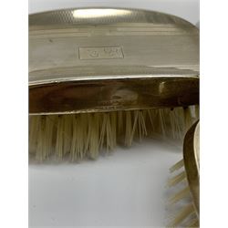 A pair of silver mounted clothes brushes, each with engine turned detail and monogramed central panel, and silver comb mount, all hallmarked Adie Brothers Ltd, Birmingham, date letters worn and indistinct, together with a cased set of six mother of pearl knives with silver ferrules, hallmarked William Yates Ltd, Sheffield 1916, a silver plated bottle coaster, with pierced sleeve and twin handles, marked beneath for Daniel and Arter, Birmingham, and a set of six silver plated coffee bean spoons. 