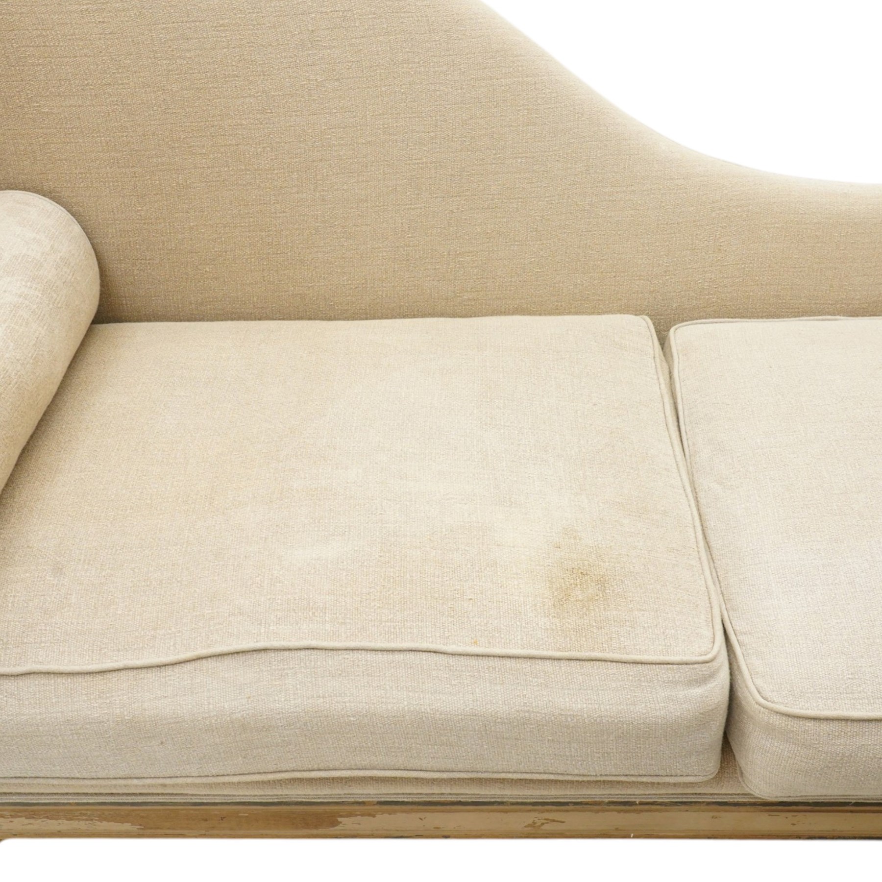 19th century French painted day bed, asymmetrical scrolled ends flanking a serpentine upholstered back, with upholstered end panels, loose seat cushions and cylindrical bolsters upholstered in beige fabric, with turned uprights with fluted detailing, moulded seat rail and lozenge-moulded corner blocks, raised on turned tapering supports