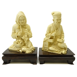  Pair Japanese Meiji period ivory Okimonos, each carved as one piece, depicting a seated woman selling fruit and seated bookbinder, both with incised seal marks to base, on hardwood stands, H11cm x W16cm and H15.5cm x W10cm   
