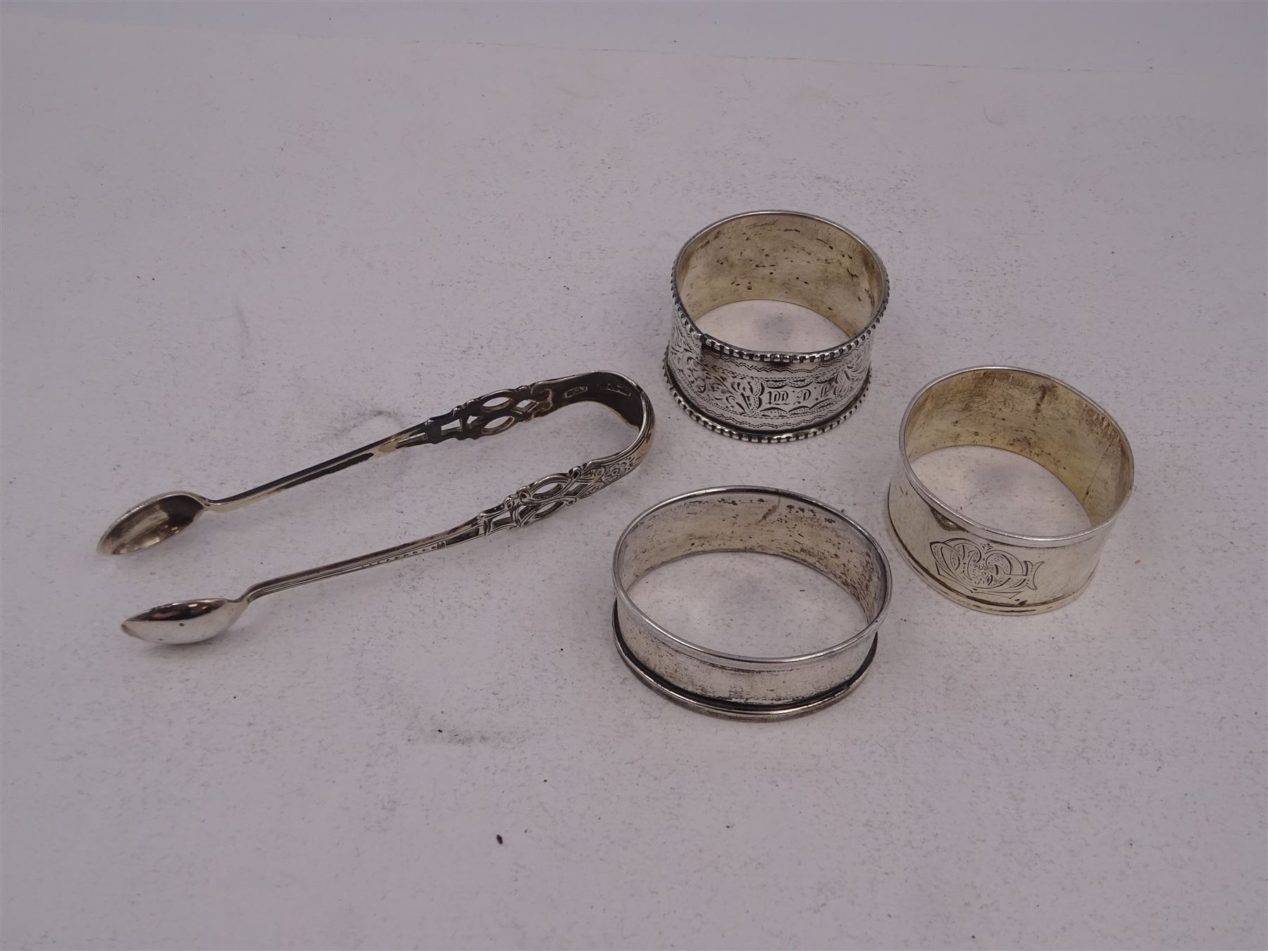 Pair of Victorian silver sugar tongs, with pierced decoration, hallmarked Hilliard & Thomason, Birmingham 1892, together with three hallmarked silver napkin rings